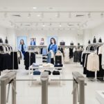 Loja de roupas com catracas na entrada e sistema de segurança discreto no ambiente.