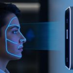 Pessoa passando por reconhecimento facial com scanner iluminado projetando linhas azuis no rosto.