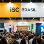 Vista panorâmica do pavilhão da feira ISC Brasil com público circulando entre estandes de segurança eletrônica e tecnologia.